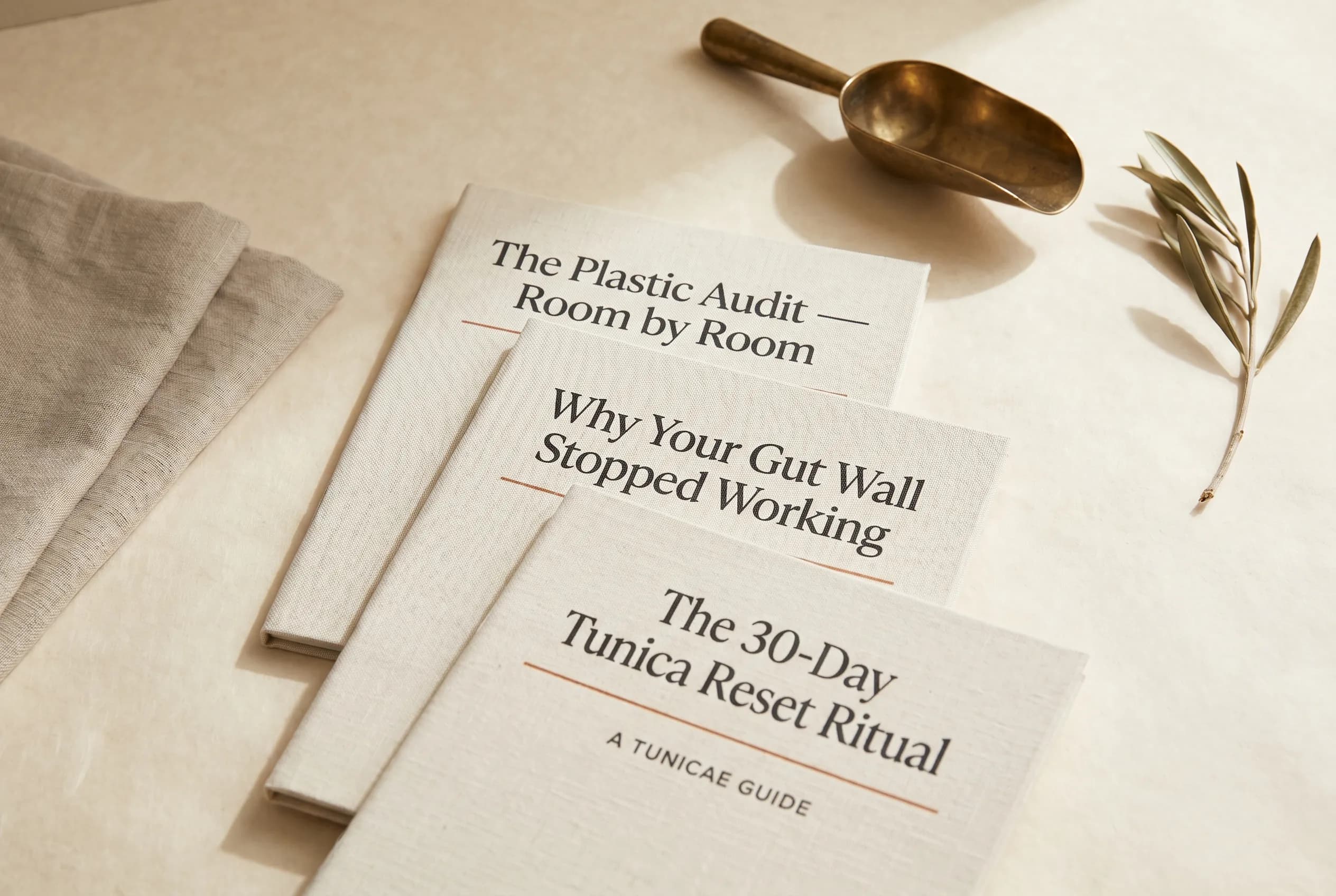 The three TUNICAE guide booklets fanned on cream parchment
